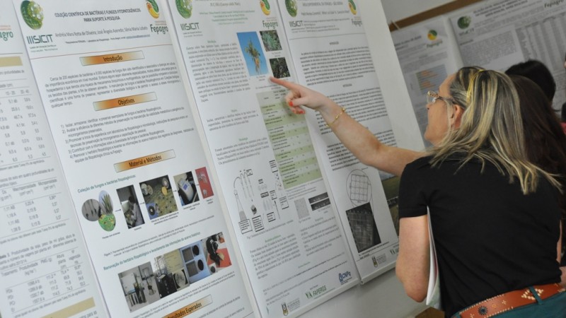 Estudante explica conte&uacute;do de p&ocirc;ster para visitante